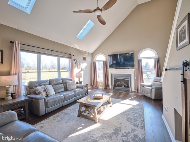 living room featuring a wealth of natural light, dark wood-type flooring, ceiling fan, and a skylight