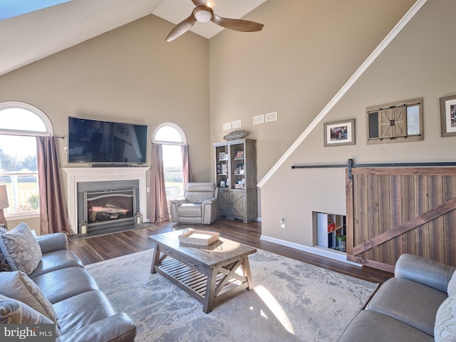 living room featuring a barn door, high vaulted ceiling, ceiling fan, and hardwood / wood-style floors