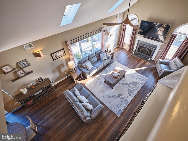 living room with high vaulted ceiling, dark hardwood / wood-style floors, and a skylight