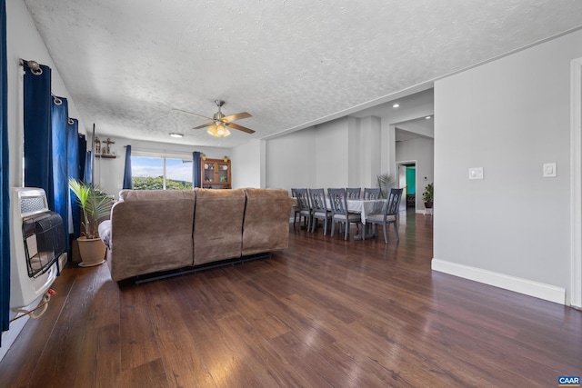 living room featuring dark hardwood / wood-style flooring, ceiling fan, and a textured ceiling