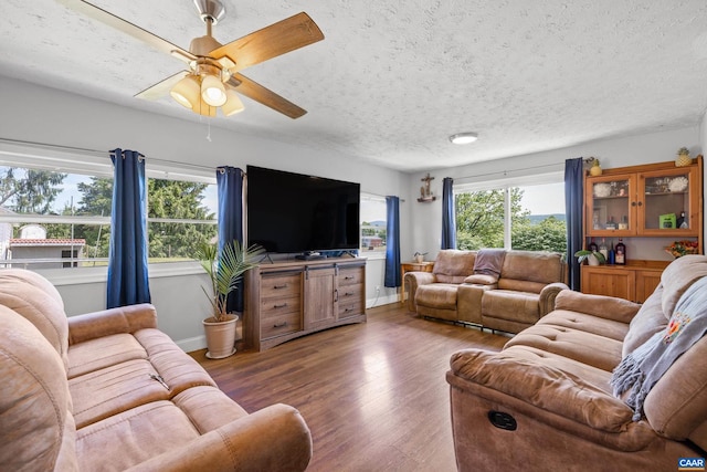 living room with a textured ceiling, ceiling fan, and dark hardwood / wood-style floors