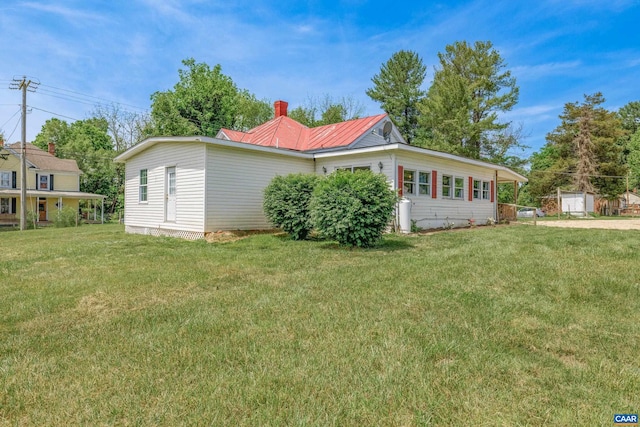 view of side of property featuring a lawn and a storage shed