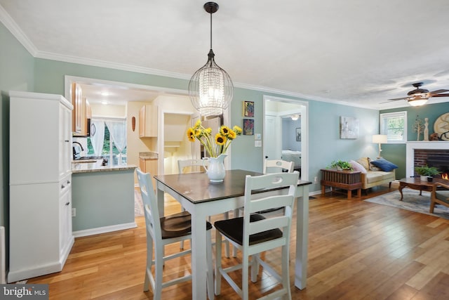 dining room with a fireplace, ceiling fan with notable chandelier, crown molding, and a healthy amount of sunlight