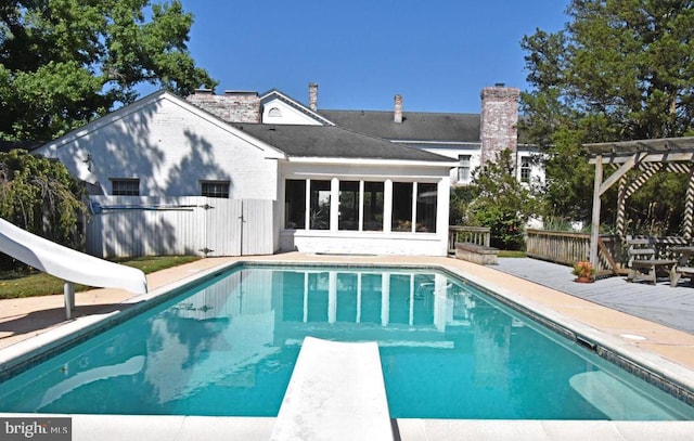 view of pool featuring a water slide, a diving board, and a pergola