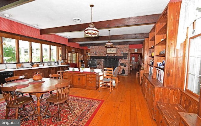 dining area with a fireplace, brick wall, beamed ceiling, built in shelves, and wood-type flooring