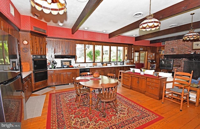 interior space with beamed ceiling, light hardwood / wood-style floors, a fireplace, and brick wall