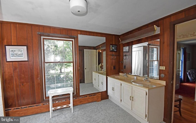 kitchen featuring sink, wooden walls, and light hardwood / wood-style floors