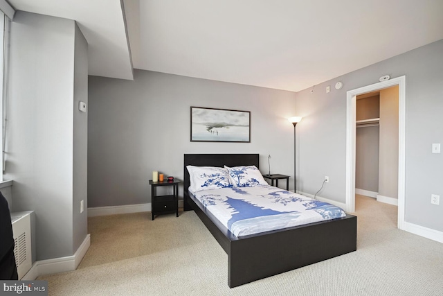 carpeted bedroom featuring a walk in closet and a closet