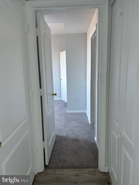 hall featuring dark colored carpet