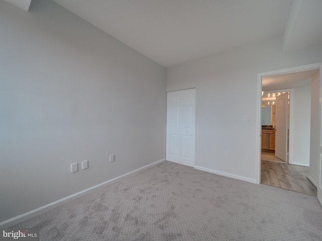 unfurnished bedroom with light carpet and a closet