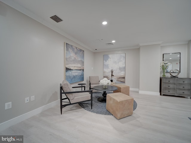 sitting room with ornamental molding and light wood-type flooring