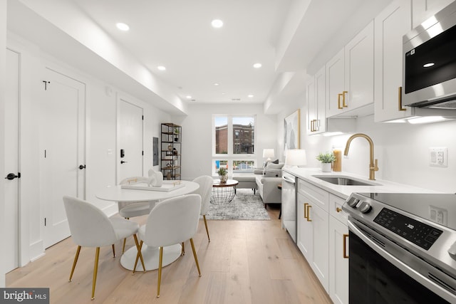 kitchen with stainless steel appliances, light hardwood / wood-style flooring, white cabinets, and sink