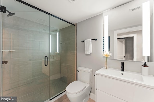 bathroom featuring a shower with door, vanity with extensive cabinet space, and toilet