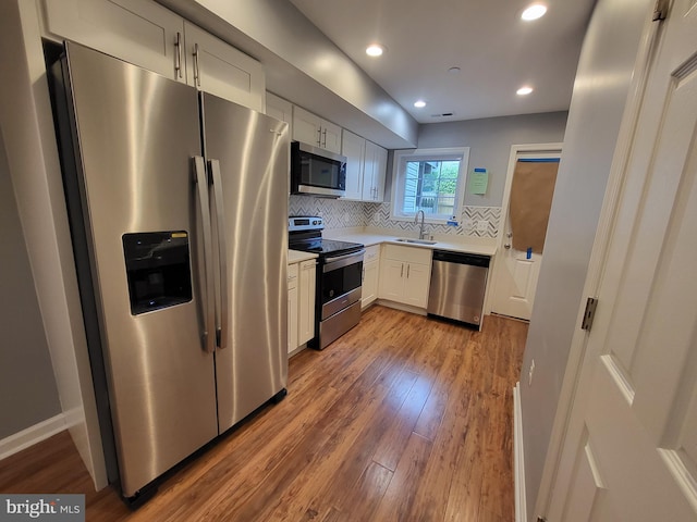 kitchen featuring sink, tasteful backsplash, hardwood / wood-style flooring, and appliances with stainless steel finishes