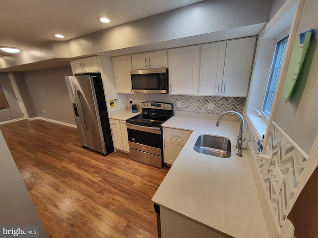 kitchen featuring stainless steel appliances, sink, hardwood / wood-style flooring, and white cabinets