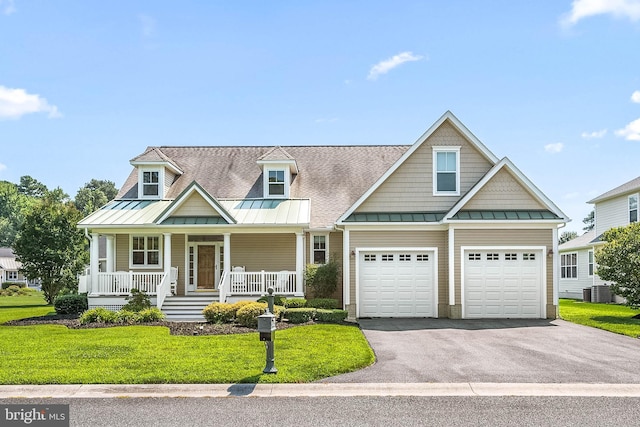 view of front of house with central AC, a garage, covered porch, and a front lawn