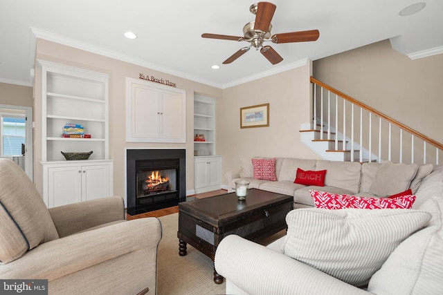 living room with wood-type flooring, ornamental molding, built in features, and ceiling fan