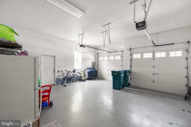 garage with a garage door opener and white refrigerator