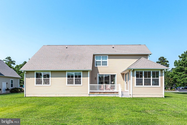 rear view of property featuring a wooden deck and a lawn