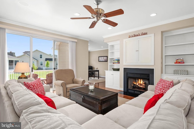 living room with crown molding, wood-type flooring, and built in shelves