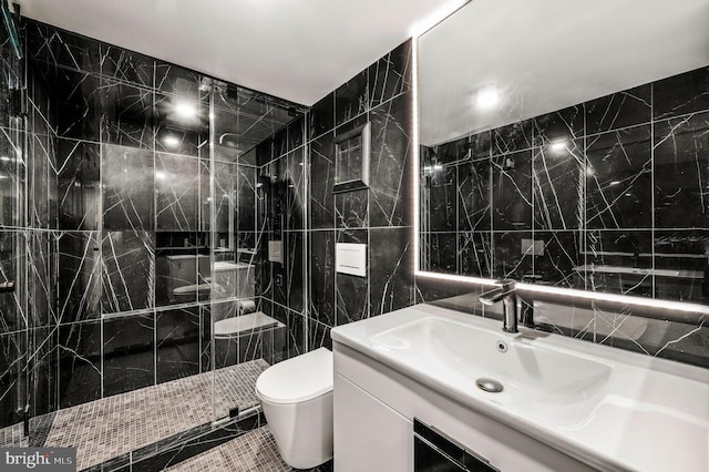 bathroom with tile walls, vanity with extensive cabinet space, toilet, tile flooring, and an enclosed shower