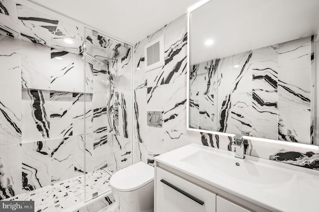 bathroom featuring tile walls, a tile shower, vanity, and toilet