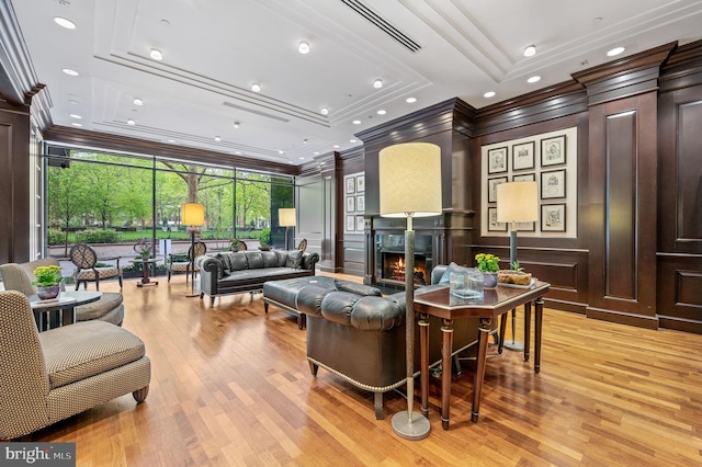 living room with crown molding, expansive windows, a raised ceiling, and light hardwood / wood-style flooring