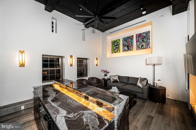 living room featuring dark hardwood / wood-style floors, beamed ceiling, and a high ceiling