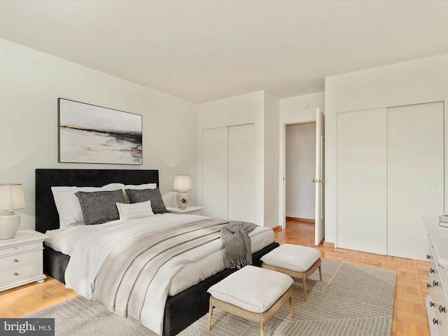 bedroom featuring two closets and parquet flooring