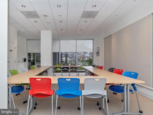 dining area with floor to ceiling windows, a wealth of natural light, and a drop ceiling