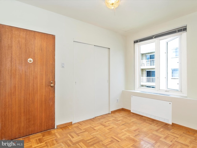 unfurnished bedroom with radiator and light parquet flooring