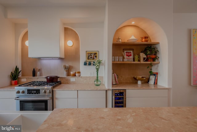 kitchen with decorative backsplash, high end stainless steel range oven, white cabinetry, and beverage cooler