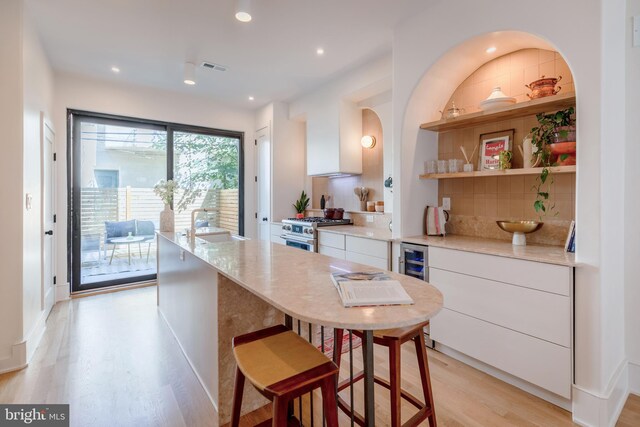 kitchen featuring high end stove, decorative backsplash, and white cabinets