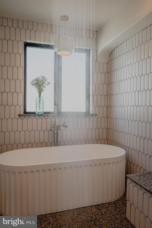 bathroom with a bath, tile walls, and plenty of natural light