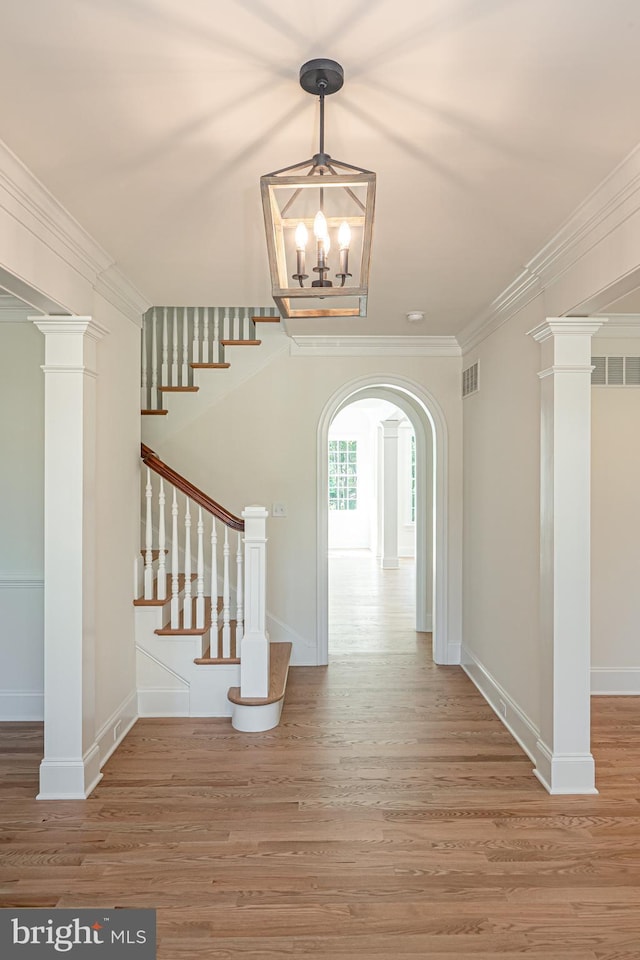 foyer entrance featuring hardwood / wood-style floors, crown molding, and a chandelier