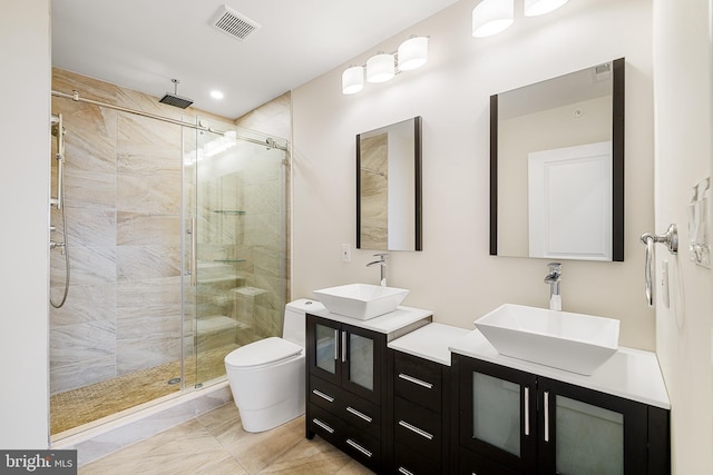 bathroom featuring a shower with shower door, double vanity, toilet, and tile floors