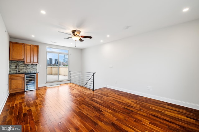 unfurnished living room featuring dark hardwood / wood-style floors, wine cooler, ceiling fan, and sink