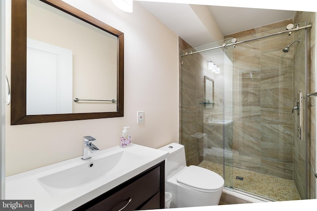 bathroom featuring vanity with extensive cabinet space, toilet, and a shower with door