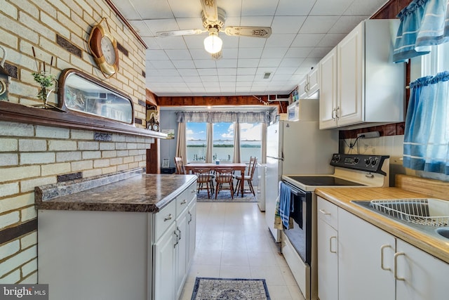 kitchen featuring brick wall, ceiling fan, white cabinetry, white range with electric cooktop, and light tile floors