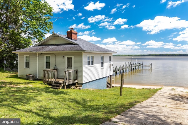 rear view of house featuring central AC unit, a lawn, and a water view