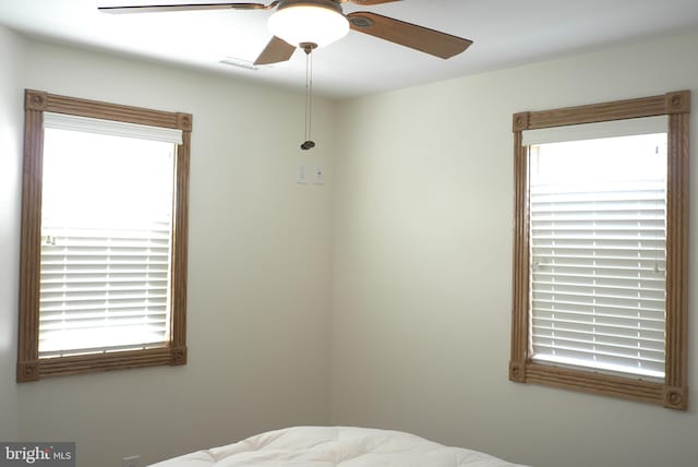 bedroom with ceiling fan and multiple windows