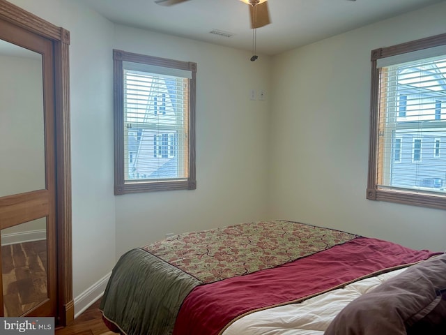 bedroom featuring ceiling fan, multiple windows, and hardwood / wood-style floors