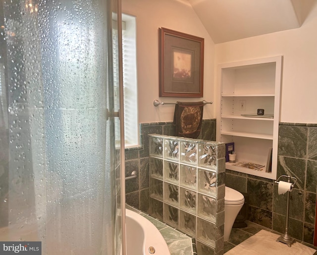 bathroom with tile floors, built in shelves, toilet, tile walls, and vaulted ceiling