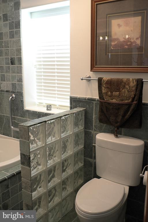 bathroom with tile walls and toilet