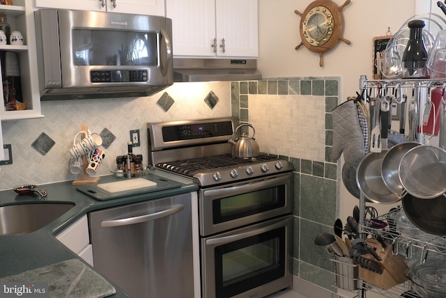 kitchen with backsplash, white cabinetry, appliances with stainless steel finishes, sink, and premium range hood