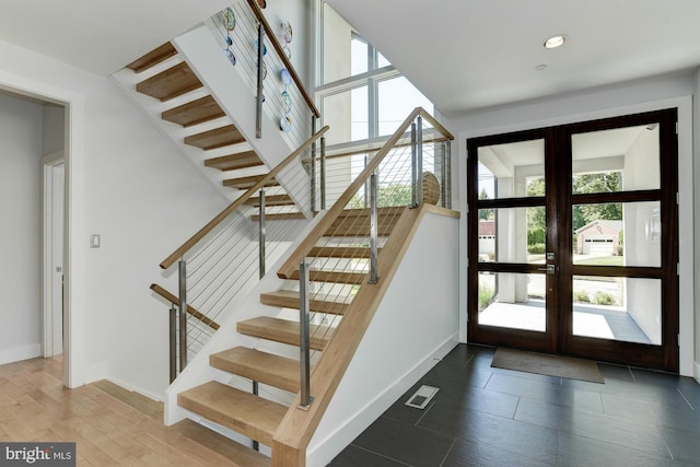 staircase with french doors and hardwood / wood-style floors