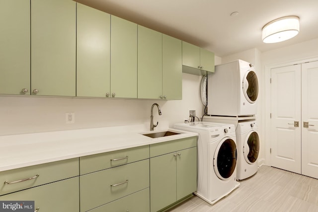 laundry area featuring cabinets, stacked washer / dryer, and sink