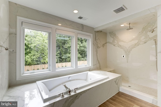 bathroom featuring plus walk in shower and hardwood / wood-style floors