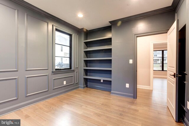 living area with built in shelves, ornamental molding, and wood-type flooring