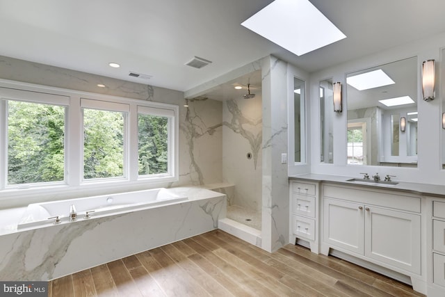 bathroom featuring plus walk in shower, vanity, and a skylight